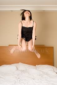 Woman jumping on bed